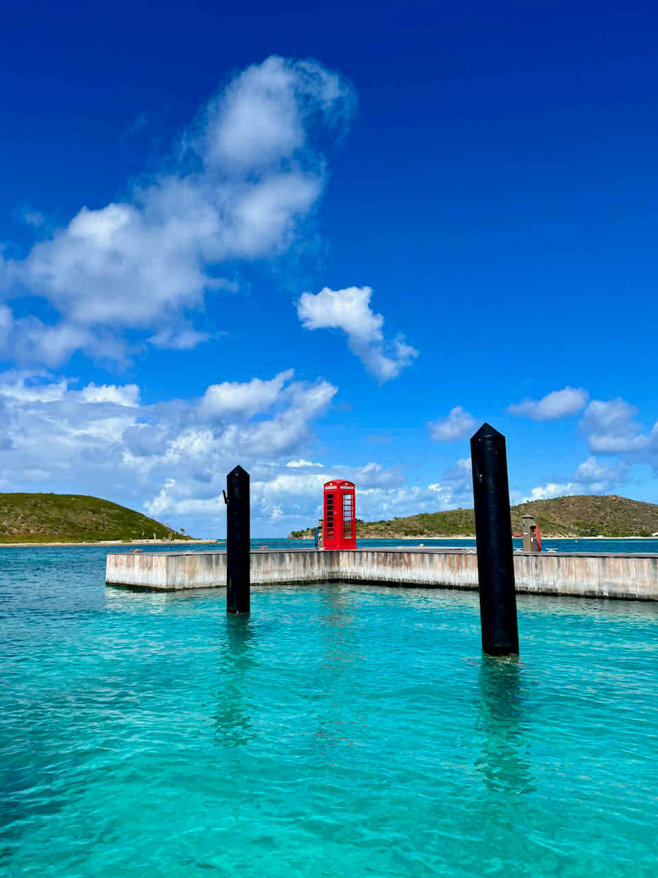 Red phone booth at Saba Rock in the British Virgin Islands with bright blue turquoise water.