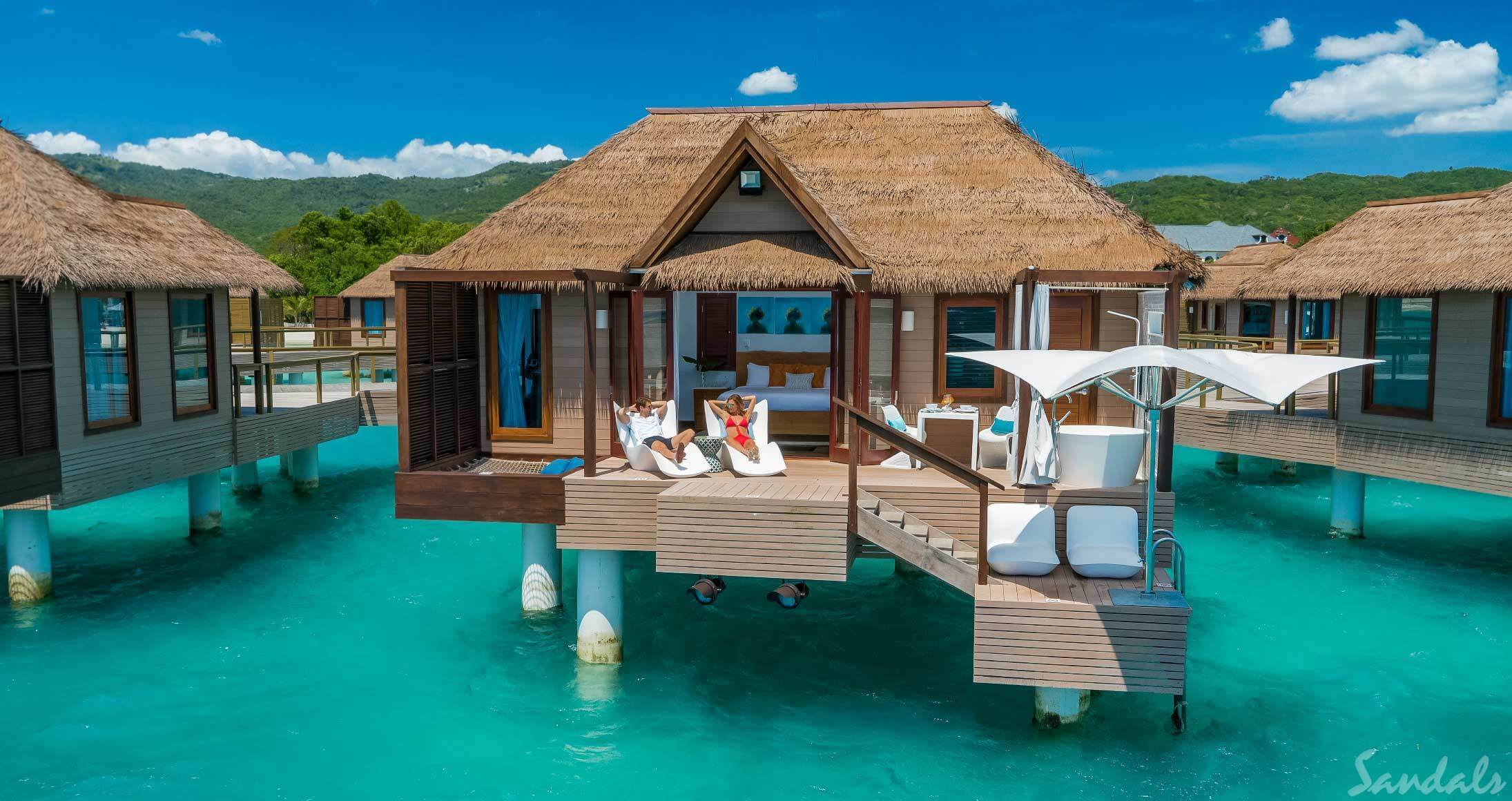 Couple relaxing at their overwater bungalow in the Caribbean at Sandals Grande St. Lucia.