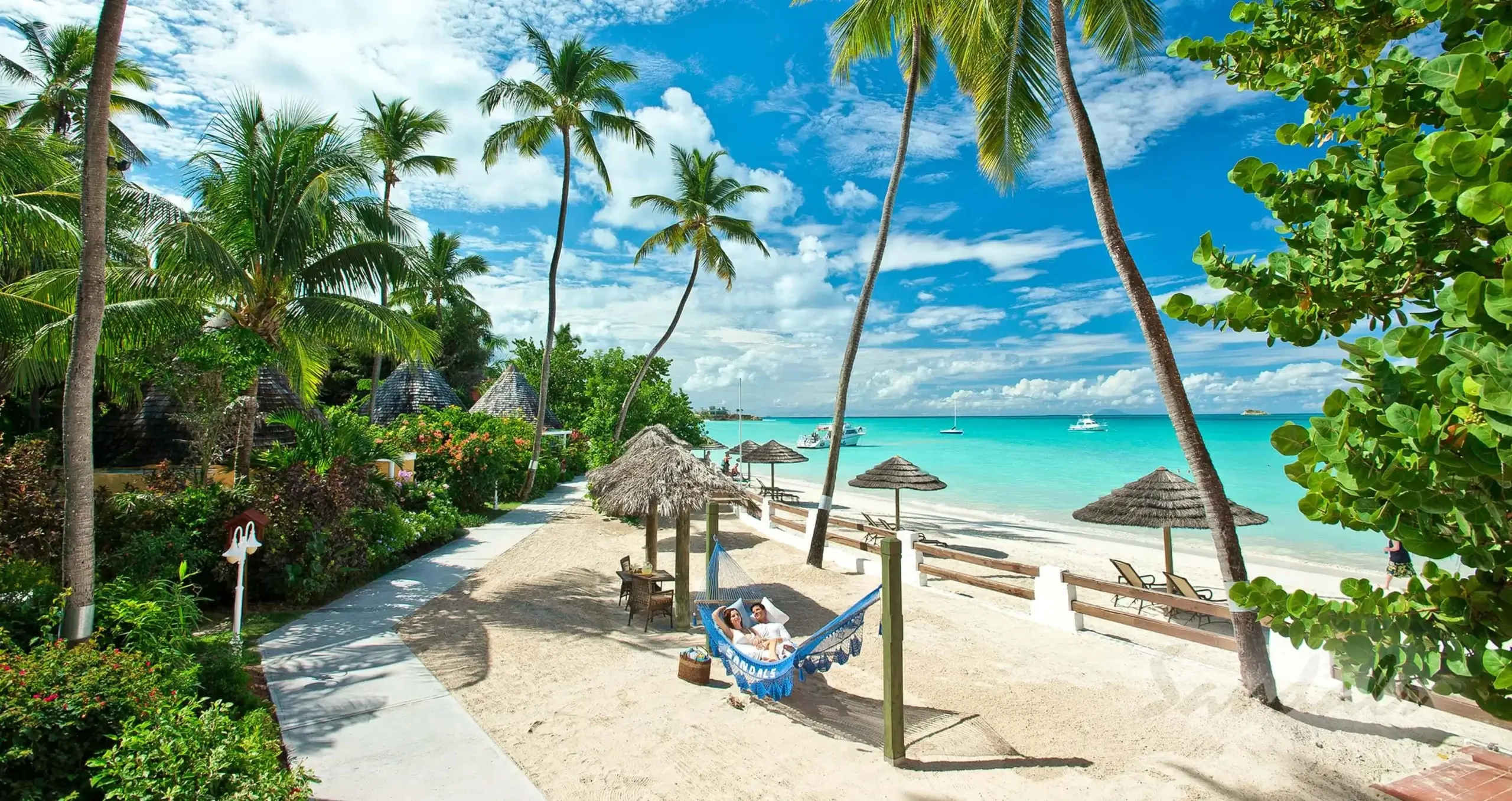 two people in a hammock on white sand beach at sandals antigua 