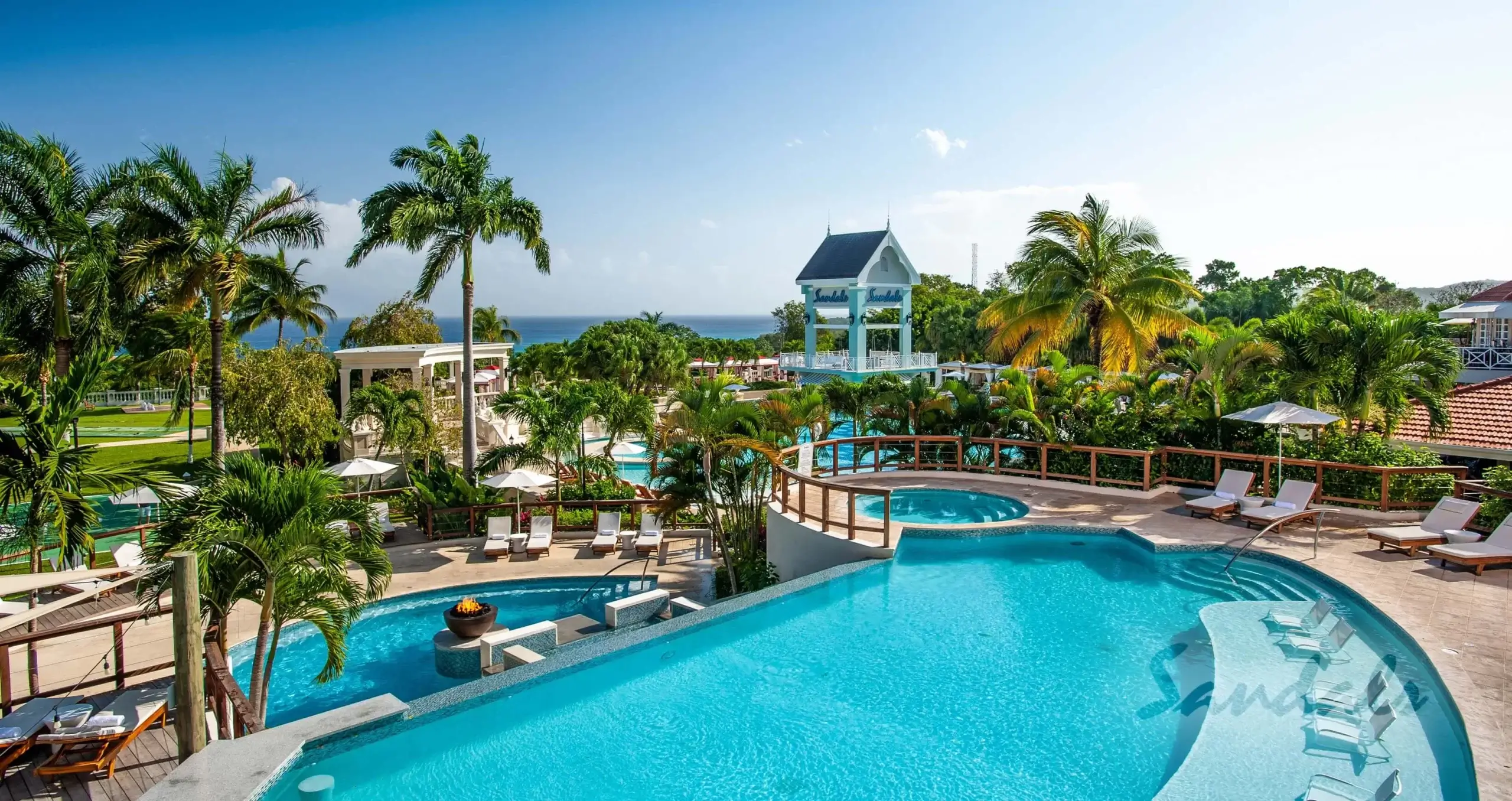 Sandals Ochi Resort with two large swimming pools and palm trees.