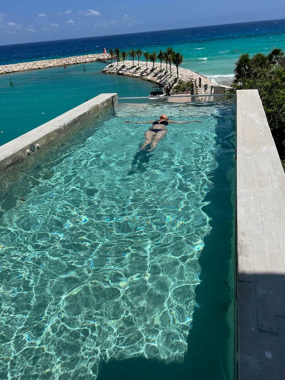 Girl floating in an infinity edge pool at La Casa de la Playa luxury hotel in Mexico.